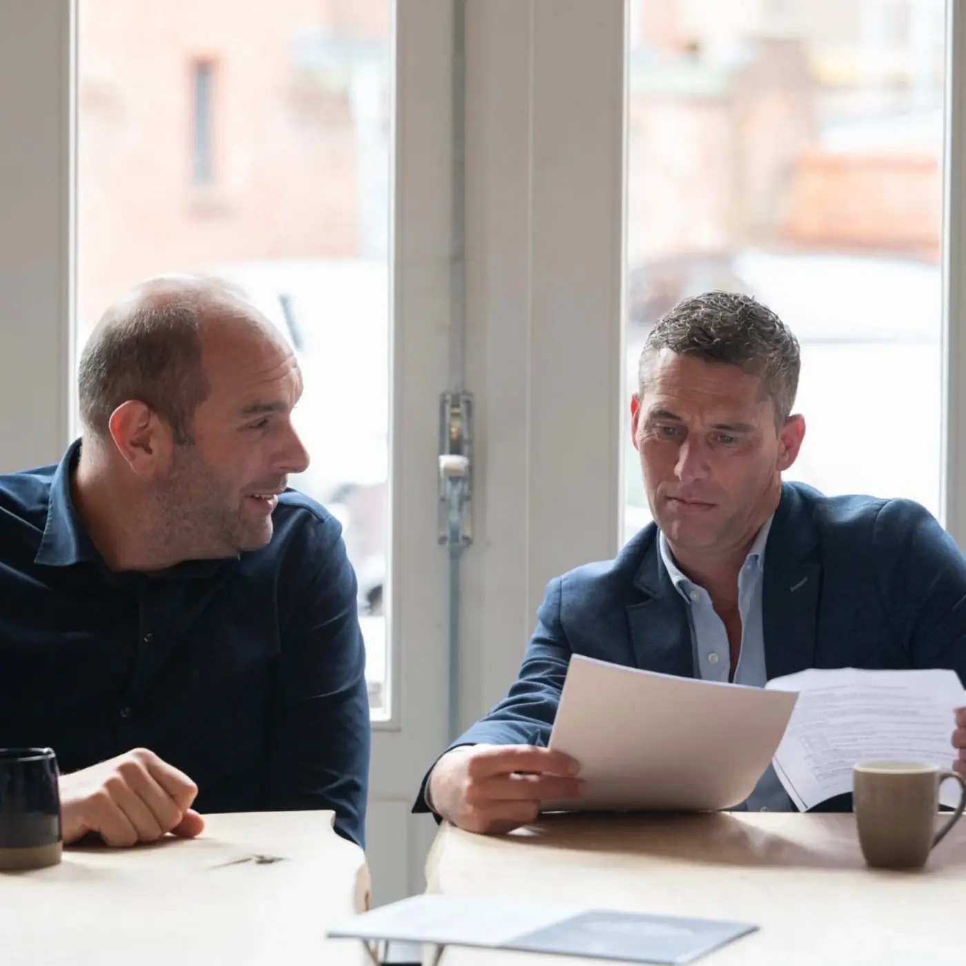 Twee experts van Schade Experts bespreken samen een schaderapport aan tafel